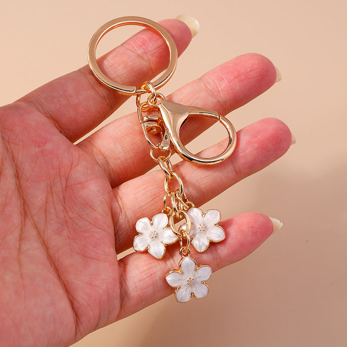 Wholesale Cherry blossom metal keychains available in various colors.